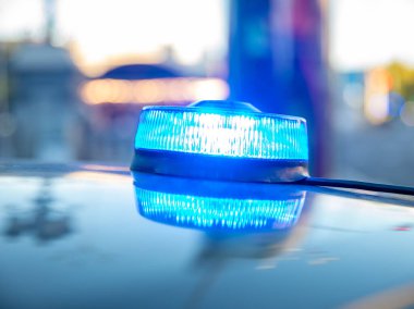 Polis arabasının tepesindeki mavi ışıklar. Arka plan bulanık. Işıklar da bokeh etkisi yapıyor.