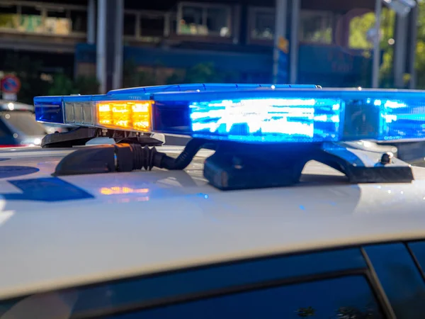 Polis arabasının tepesindeki mavi ışıklar. Arka plan bulanık. Işıklar da bokeh etkisi yapıyor.