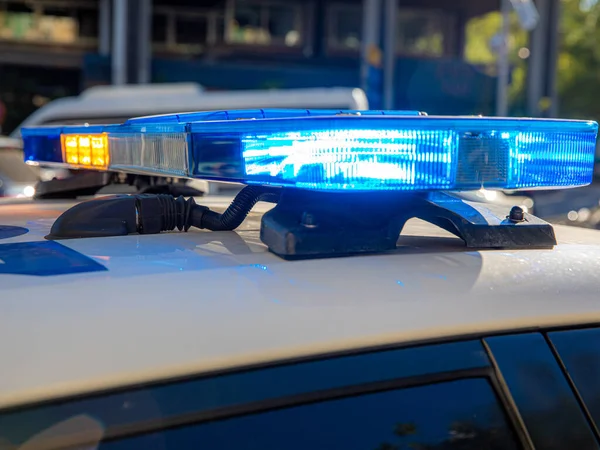 Polis arabasının tepesindeki mavi ışıklar. Arka plan bulanık. Işıklar da bokeh etkisi yapıyor.