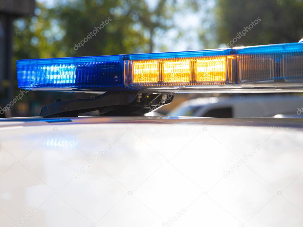 blue lights on the roof of a police car with the background out of focus and lights with bokeh effect