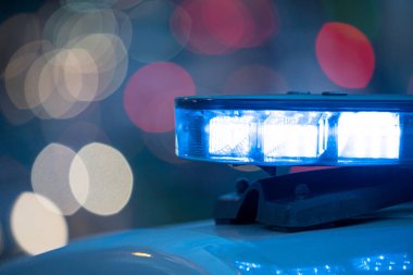 Polis arabasının tepesindeki mavi ışıklar. Arka plan bulanık. Işıklar da bokeh etkisi yapıyor.