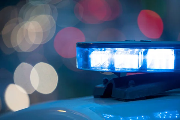 Polis arabasının tepesindeki mavi ışıklar. Arka plan bulanık. Işıklar da bokeh etkisi yapıyor.