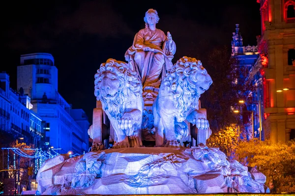 İspanya 'nın başkenti Madrid' deki sembolik Plaza de Cibeles 'de karanlık bir kış gecesinde iki aslan ve Noel ışıklandırmasıyla tanrıça Cibeles' in heykeli.