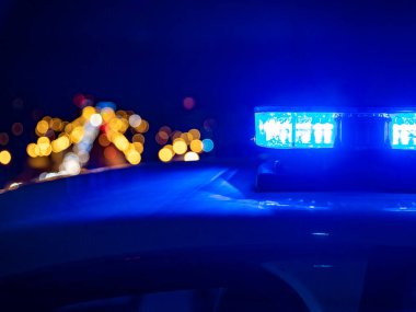 Polis arabasının tepesindeki mavi ışıklar. Arka plan bulanık. Işıklar da bokeh etkisi yapıyor.