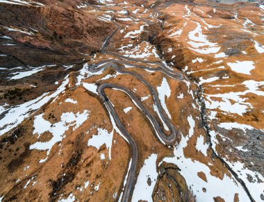 Formigal kayak merkezindeki kıvrımlı dağ yolu, karlı bir manzara ve bulutlu mavi bir gökyüzü.
