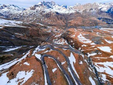Formigal kayak merkezindeki kıvrımlı dağ yolu, karlı bir manzara ve bulutlu mavi bir gökyüzü.