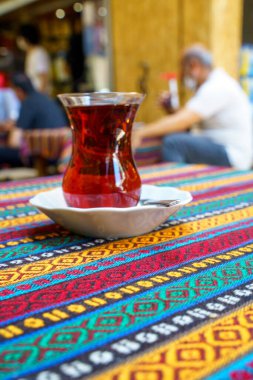 Small glass of Turkish red tea on a table with a colorful tablecloth