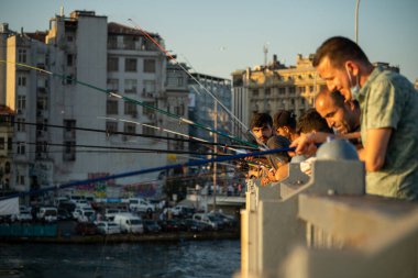 İstanbul, Türkiye 'deki Galata köprüsünde oltaları olan balıkçılar