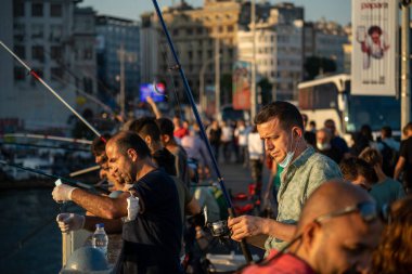 İstanbul, Türkiye 'deki Galata köprüsünde oltaları olan balıkçılar