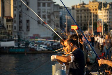 İstanbul, Türkiye 'deki Galata köprüsünde oltaları olan balıkçılar