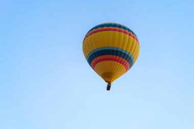 Colorful balloon flying over a clear blue sky during a sunset on a sunny day in Cappadocia, Turkey, copy space