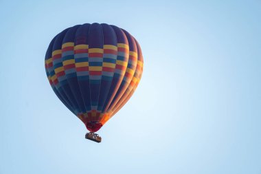 Colorful balloon flying over a clear blue sky during a sunset on a sunny day in Cappadocia, Turkey, copy space