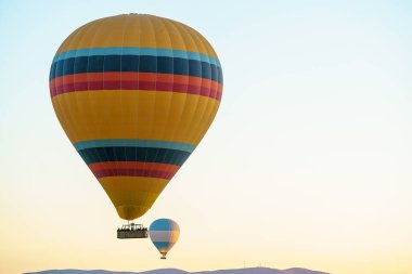 Set of colorful balloons flying over Goreme city in Cappadocia, during sunset on a clear summer day, copy space
