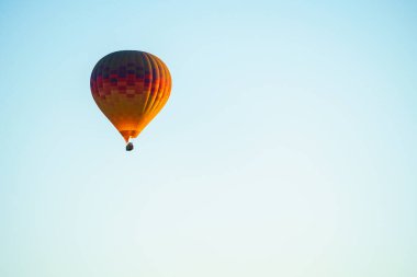Balloons burning fuel as they fly over the city of Goreme with sightseeing tourists during a sunny summer day
