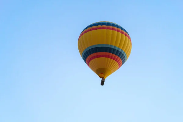 在土耳其卡帕多西亚 一个阳光灿烂的日子 一个色彩斑斓的气球在晴朗的蓝天上飞翔 复制着太空 — 图库照片