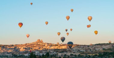 Set of colorful balloons flying over Goreme city in Cappadocia, during sunset on a clear summer day, copy space