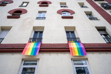 LGTBI haklarının savunulması lehine renkli bayraklar ve Madrid şehrindeki bir apartman bloğunun ön cephesinde ikili olmayan insanlar.