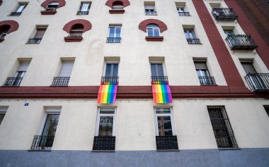 LGTBI haklarının savunulması lehine renkli bayraklar ve Madrid şehrindeki bir apartman bloğunun ön cephesinde ikili olmayan insanlar.