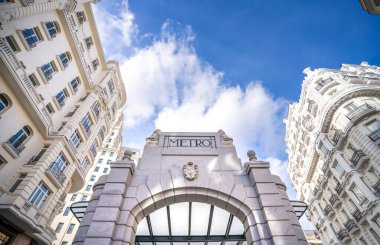 Madrid 'deki Gran Va metro istasyonunun tarihi gölgesi, Telefnica binası ve Gran Va caddesinin mavi gökyüzü ile güneşli bir günde manzarası