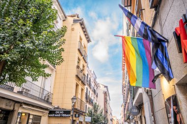 LGTBI haklarının savunulması lehine renkli bayraklar ve Madrid şehrindeki bir apartman bloğunun ön cephesinde ikili olmayan insanlar.
