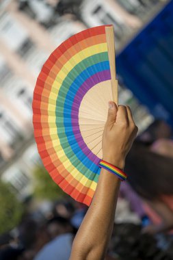 Çok renkli gay bayrağı olan bir kadın, bir gökkuşağı bileziği ve çok renkli tırnakları olan, neşeli ve LGBTİ gururlu bir yaz gününde,