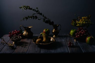 Fruit still life with grapes, apples, pears, chocolate and antique copper utensils on dark wooden table background