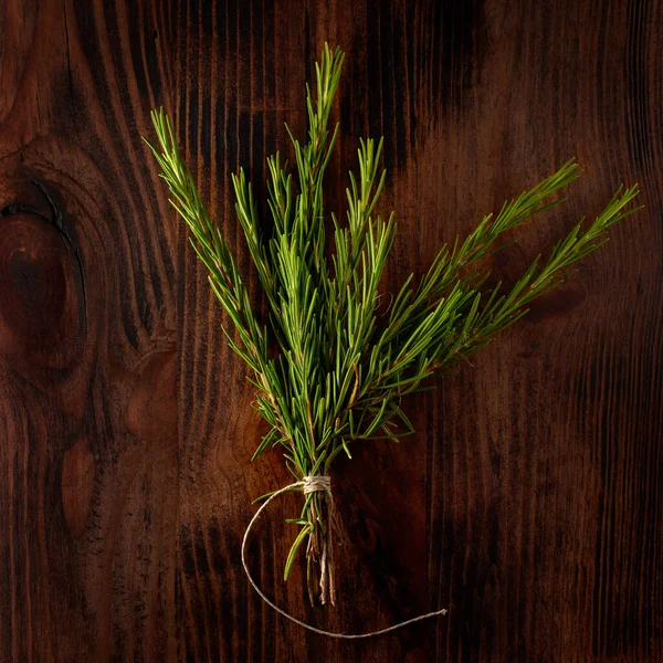 Green bouquet of rosemary on dark wooden table background
