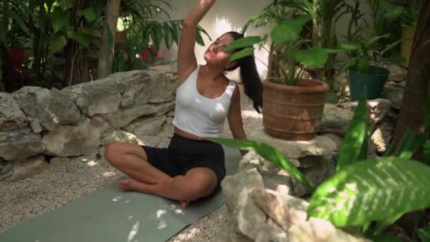 Junge hispanische Frau sitzt auf Yogamatte und dehnt sich vor Yoga-Kurs — Stockvideo