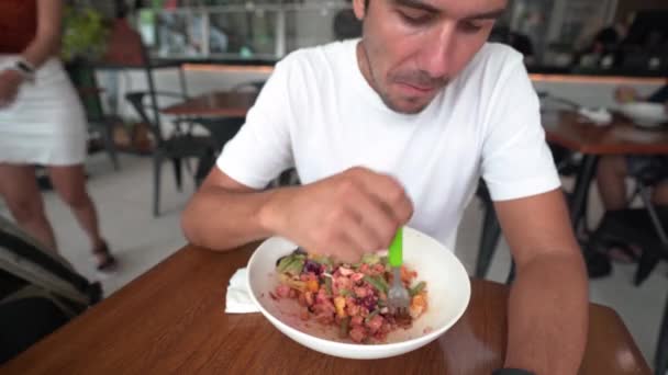 Jovem hispânico homem com boné come salada em um restaurante - estilo de vida saudável — Vídeo de Stock