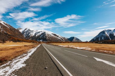 A road in the mountains with beautiful landscapes and views of rocks and peaks in Altai in autumn