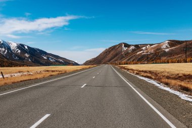 A road in the mountains with beautiful landscapes and views of rocks and peaks in Altai in autumn
