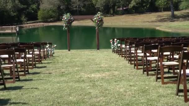 Outdoor wedding ceremony setting by lake chairs — Stock Video