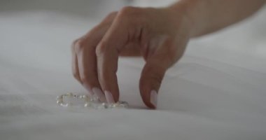 Düğün için. Yakın çekim. Gelin, güzel beyaz bir gelinlik giyerken bileziği ayarlıyor.