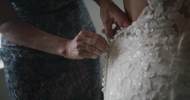 Moeder knoop lacy dure trouwjurk van haar dochter, terug closeup — Stockvideo