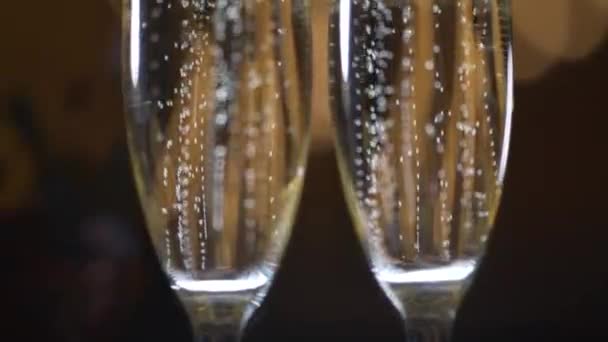 Two glasses with sparkling champaign with bubbles stand on the soft background — Stockvideo