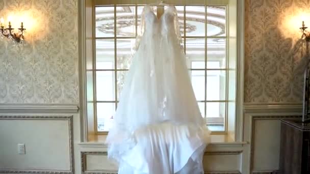 Delicate bridesmaid dress hanging above the door of an old brick building — Stock Video