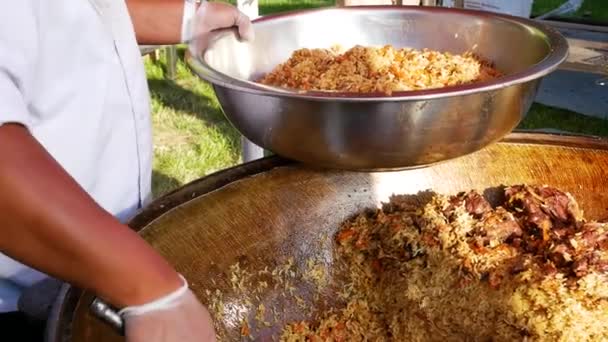Hef cook and put spanish paella on the plate with shrimp, meat, mussel, rice, spice, saffron in huge paella pan at food market. — Wideo stockowe