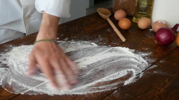 Detailní záběr pekaře nalévá mouku v kuchyni. Akce. Pekař sype špetku mouky na dřevěný stůl — Stock video