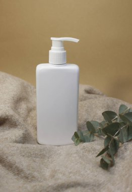 Örgü arka planda beyaz pakette cilt kremi ve losyon. Yüzü ve kuru elleri için kozmetik ürünü olan plastik beyaz bir tüp..