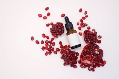 Şişe serumunda yağ. Siyah cam, sıvı için bir kap. Tahıllar ve nar parçaları. Çevresel dostluk, tazelik ve ürünün sulandırıcılığı kavramı.