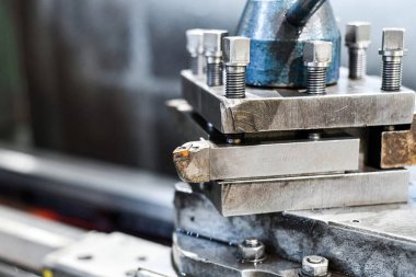 Makinede, atölyesinde cıvatalar olan metal bir parça var..