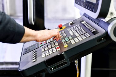 Adam CNC makinesinin uzaktan kumandasını kullanıyor..
