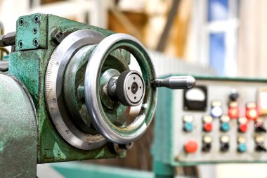 Atölyede, makinede bir besleme kontrol mekanizması var, ve arkada da bir cnc makine kontrol paneli var..