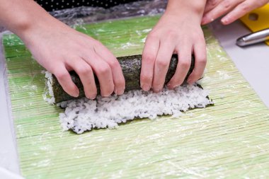 Kız neredeyse hazır suşiyi nevresim kağıdına sarmış..