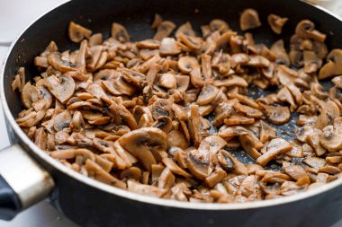 Fried chopped mushrooms lie in a frying pan.