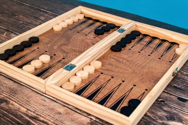 Chips for playing backgammon are laid out on a wooden board.