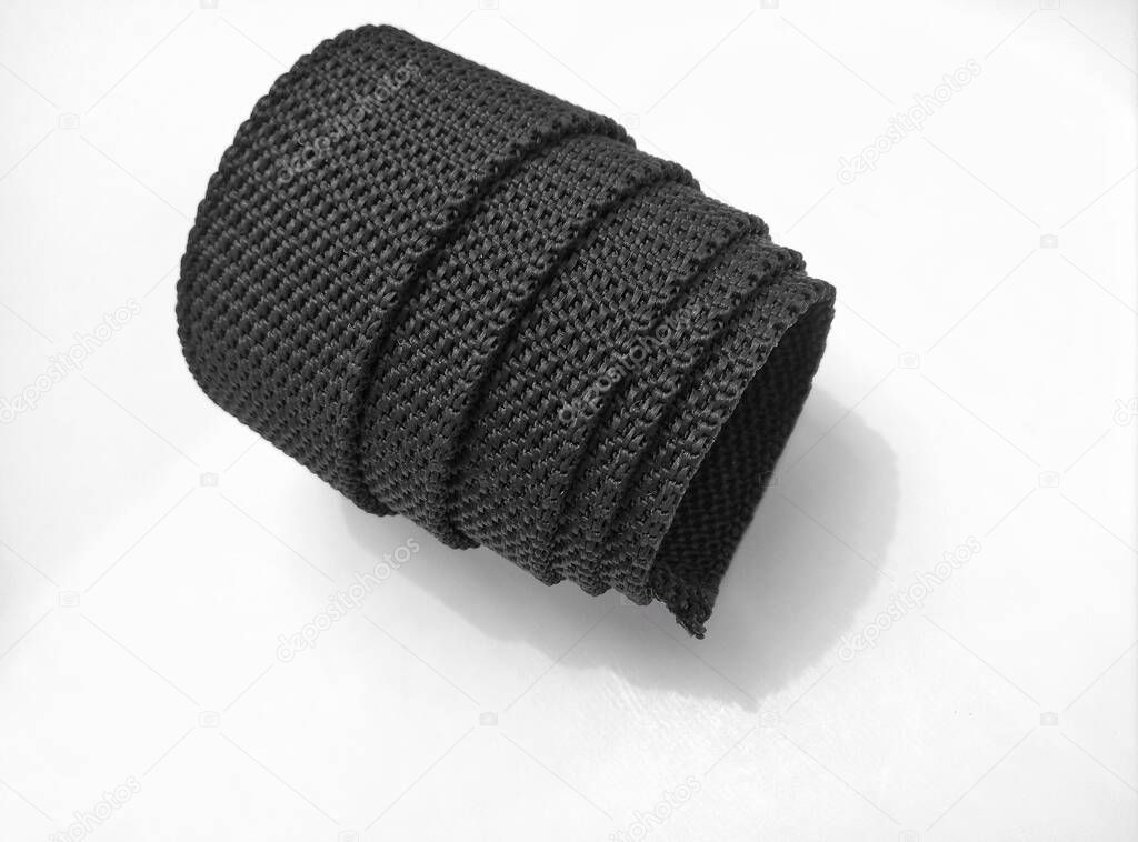 black rough textured nylon fabric belt roll isolated on a white background. spiral style roll