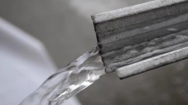 Duş alırken temiz su fışkırıyor ya da arka plandaki metal oluklar bulanıklaşıyor. dökülen su detayları