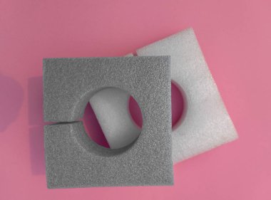 Pembe kağıtlarda delikleri olan gri ve beyaz kare köpüklü sünger. Hassas ürünleri veya ögeleri paketlemek için yumuşak ve elastik bir malzeme