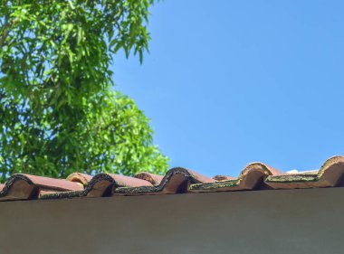 turuncu kiremit. Çatının kıvrımlı tarafı. Evin üst kapağının ayrıntıları mavi gökyüzü arka planında gür ve serin ağaçlarla birlikte kilden yapılmıştır.
